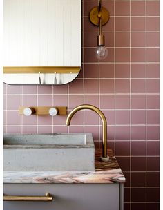 a bathroom with pink tiles and gold faucet, sink and mirror on the wall