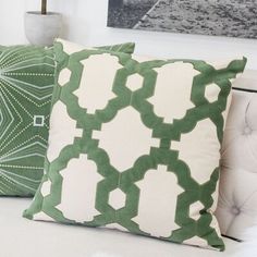 two green and white pillows sitting on top of a couch