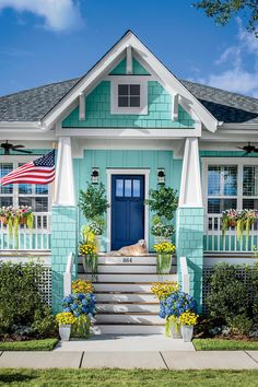 a dog is laying on the front steps of a blue house with flowers and plants