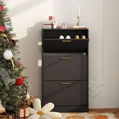 a small christmas tree in front of a black cabinet