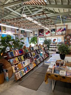 a room filled with lots of books next to a table full of potted plants