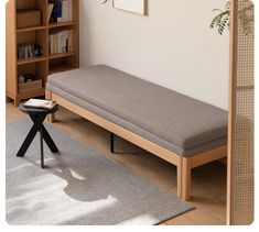 a wooden bench sitting on top of a hard wood floor next to a book shelf