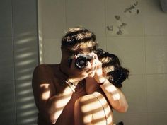 a man taking a selfie in front of a bathroom mirror with his camera attached to his neck