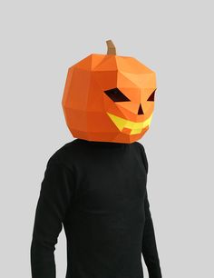 a person wearing an orange paper pumpkin mask on top of their head and black shirt