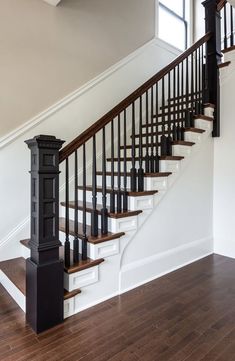 a stair case next to a wooden floor in a room with white walls and wood floors