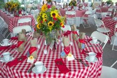 the table is set with red and white checkered cloths, sunflowers in vase