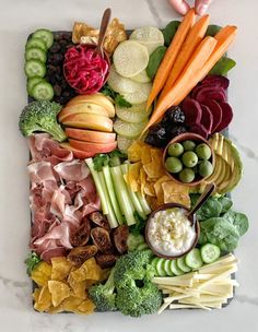 a platter filled with assorted fruits and veggies on top of a marble counter