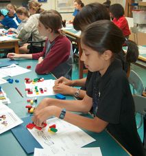 several children are sitting at a table playing with different shapes and colors