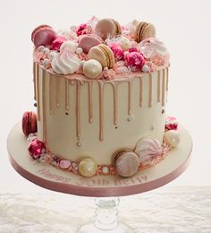 a white cake with pink icing and macaroons on top