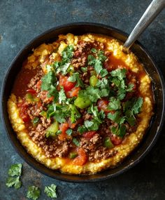 a skillet filled with food and garnished with cilantro, green peppers, and ground beef