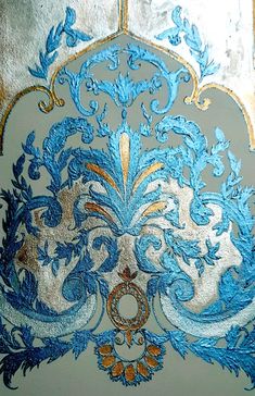 an ornate blue and gold design on a white wall