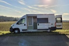 a small white van parked on the side of a road next to an open field