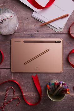 an open laptop computer sitting on top of a wooden table next to candy and ribbon