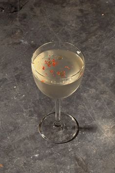 a glass filled with white wine and garnished with orange peels on the rim