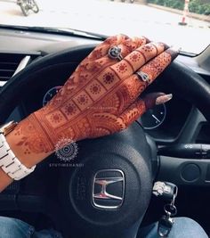 a woman with henna on her hands driving a car