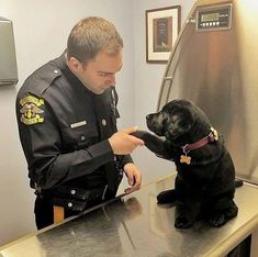 a police officer petting a black dog on the nose in front of a mirror