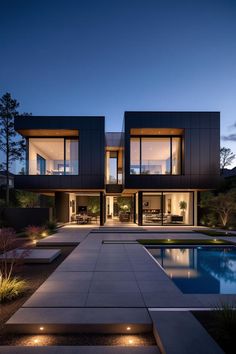 a modern house with an outdoor swimming pool and landscaping area at night in the evening