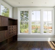 an empty room with wood flooring and large windows on both sides of the wall