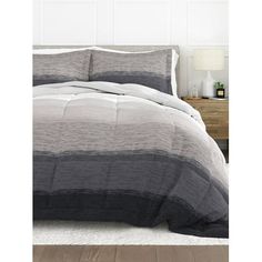 an image of a bed with grey and white comforter