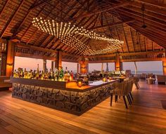 an outdoor bar with lots of bottles on the counter and lights hanging from the ceiling