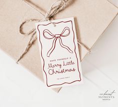 a brown envelope with a red ribbon and merry little christmas tag