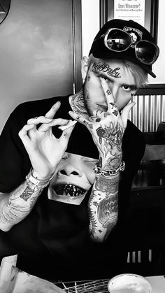 a man with tattoos on his arms and hands holding food in front of his face