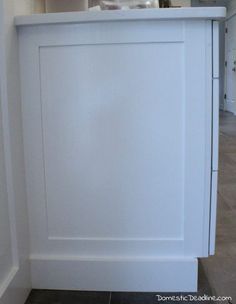 a white cabinet in the corner of a room with tile flooring and walls on both sides