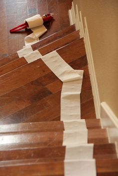 some white tape is on the floor next to wooden stairs and a red umbrella with an orange handle