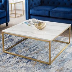 a living room with two blue couches and a white coffee table on top of a rug