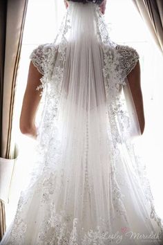 the back of a bride's wedding dress is shown in front of a window