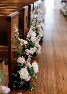 rows of pews with white and pink flowers on the bottom, along with greenery