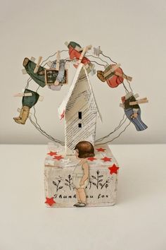 a little boy is standing in front of a house made out of paper and string