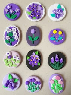 nine decorated cookies with flowers on them sitting on top of a white countertop next to each other