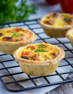 small quiche pies on a cooling rack with tomatoes and parsley in the background