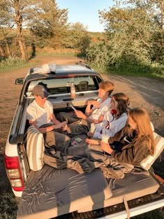 a group of people sitting in the back of a pick up truck on a dirt road