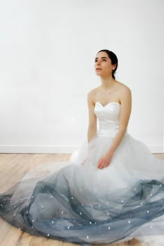 a woman in a white dress sitting on the floor with her hands behind her back