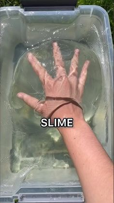 someone is holding their hand up to the water in a plastic container that says slime