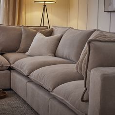 a living room couch with pillows on it and a lamp in the corner behind it