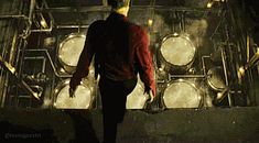 a man is walking in front of some metal pipes and drum cases with lights on them