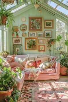 a living room filled with lots of plants and pictures on the wall above it's couch