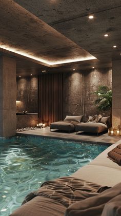 an indoor swimming pool with candles lit up on the side and couches around it