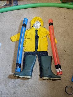 a child's raincoat and rubber boots are laid out on the floor