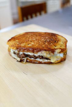 a grilled cheese sandwich sitting on top of a wooden cutting board