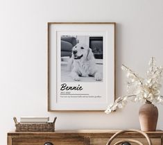 a white dog sitting on top of a wooden dresser next to a vase filled with flowers