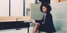 a woman sitting on top of a white bench next to a table with a laptop