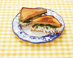 a sandwich on a plate with lettuce and other toppings sitting on a checkered tablecloth