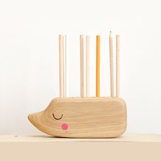 a wooden toothbrush holder with two pencils sticking out of it's sides