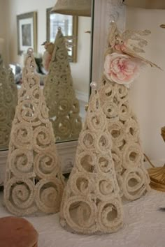 three crocheted christmas trees sitting on top of a table next to a mirror