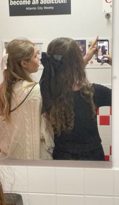 two young women are looking at their selfies in the mirror