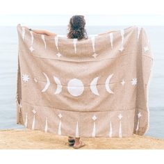 a woman wrapped up in a towel with the moon and stars on it by the water